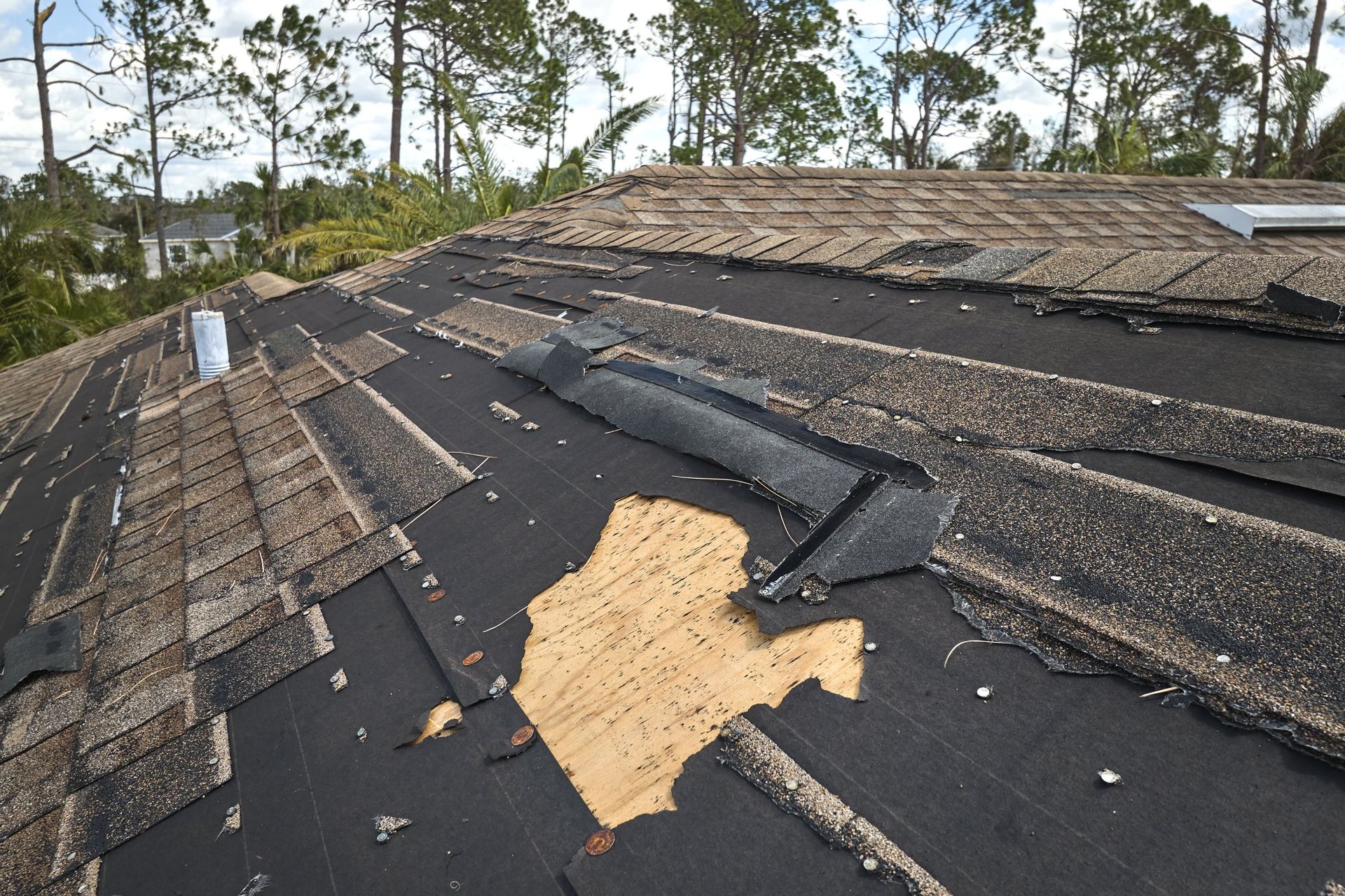 Storm-damaged roof with missing shingles after a hurricane
